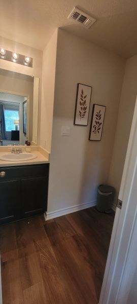 A cozy bathroom featuring a sleek vanity, elegant lighting, and warm wooden flooring.