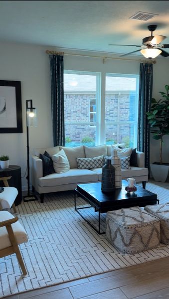 A cozy living room with a plush sofa, patterned cushions, and chic coffee table decor under soft natural light.