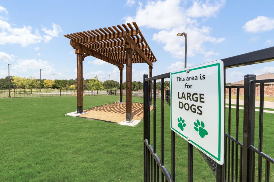Fenced large dog park with green grass, wooden pergola, and entry sign reading "This area is for Large Dogs"