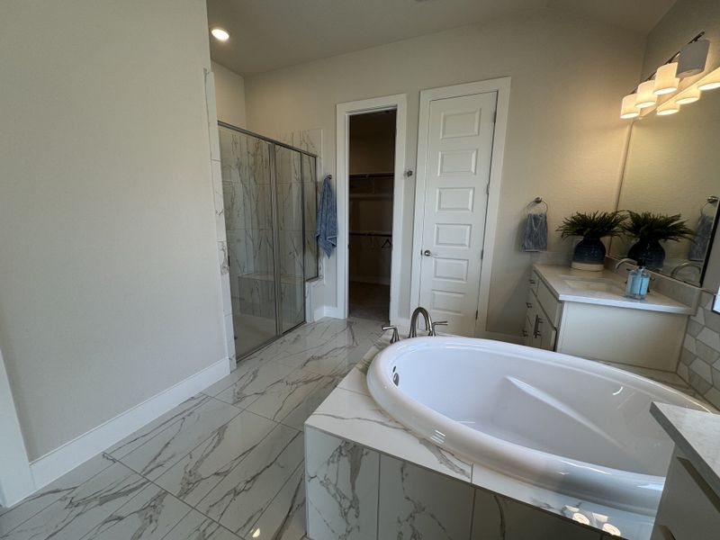 A modern bathroom with a luxurious oval tub, marble flooring, sleek shower, and elegant lighting.