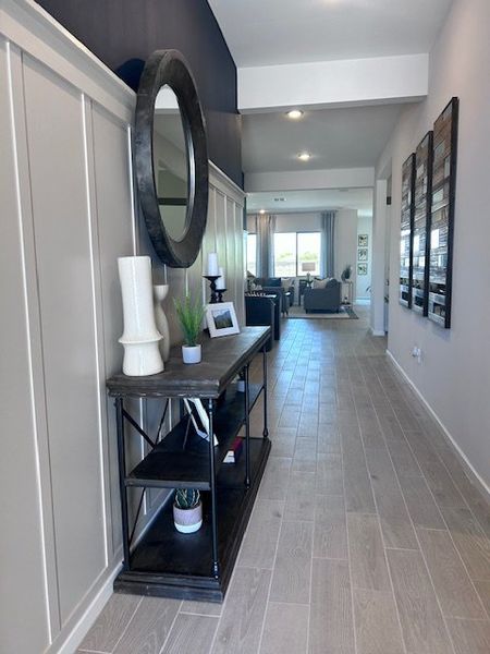 A modern hallway with sleek decor, featuring a rustic console table, large mirror, and tile flooring leading to a bright living area. A modern hallway with sleek decor, featuring a rustic console table, large mirror, and tile flooring leading to a bright living area.