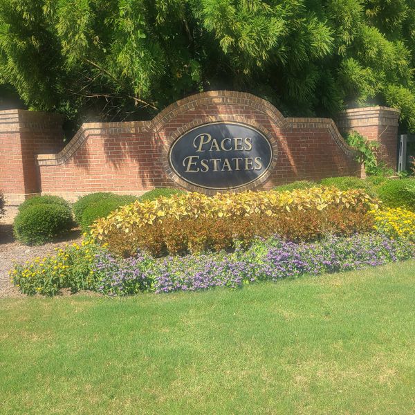 A welcoming brick entrance with vibrant landscaping in Paces Estates by McKinley Homes (Lithia Springs, GA).