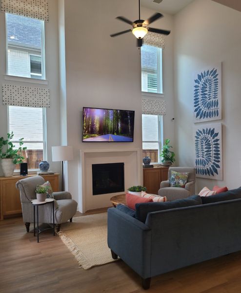 A cozy living room with high ceilings, a fireplace, modern decor, and large windows letting in natural light.