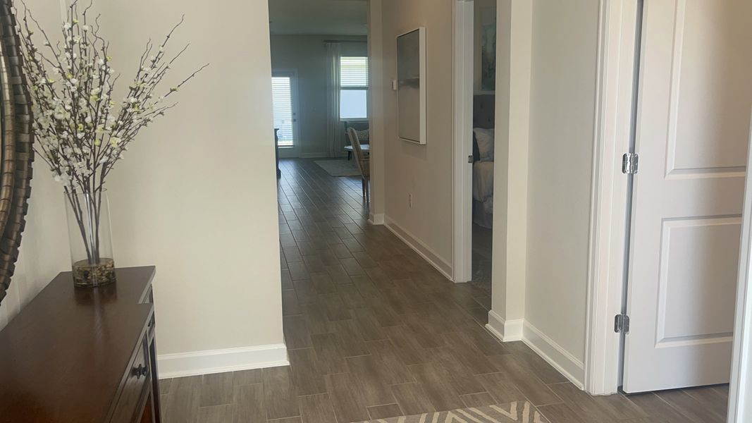 A welcoming hallway with elegant wood flooring, white walls, and decorative accents.