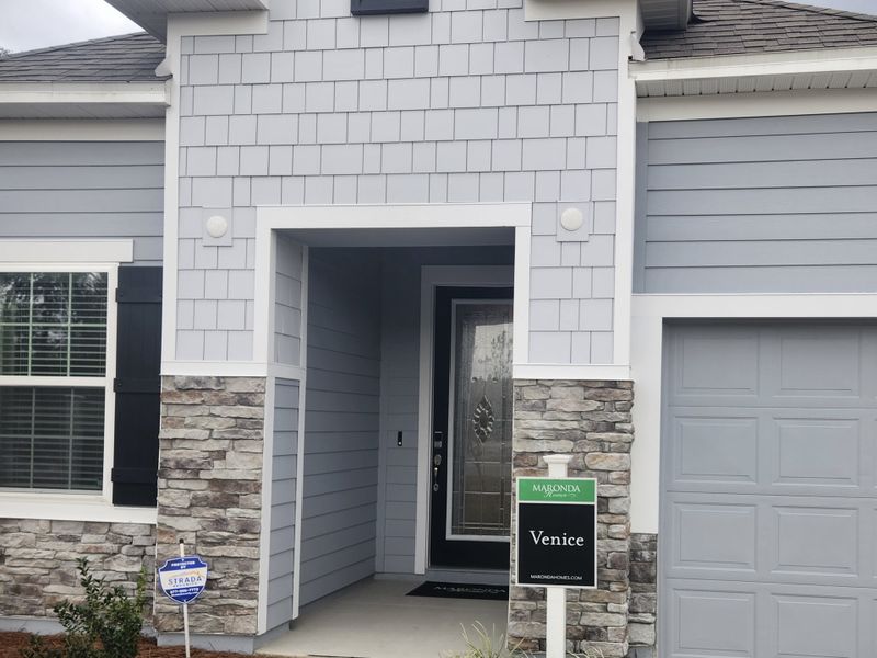 Charming gray home with stone accents and modern design in Creekside Landing by Maronda Homes (Callahan, FL).