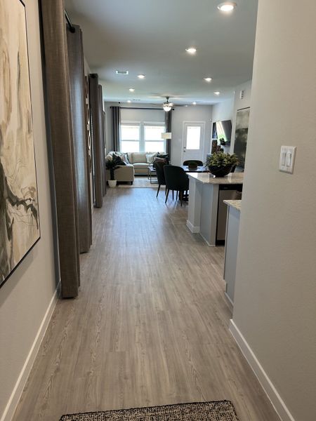 A modern interior with light wood floors, cozy seating, and elegant décor, leading to a bright living area.