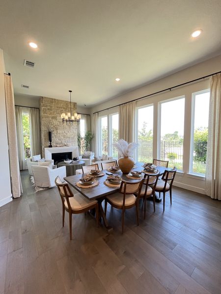 A spacious dining and living area with large windows, a stone fireplace, and elegant decor, offering a warm, inviting atmosphere.