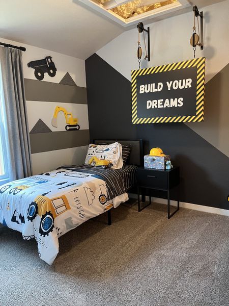 A playful children’s room with construction-themed decor, gray walls, and cozy bedding.