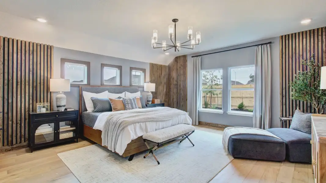 Experience refined comfort with modern chandelier lighting, wood accents, and expansive windows in Sunflower Ridge's master suite.