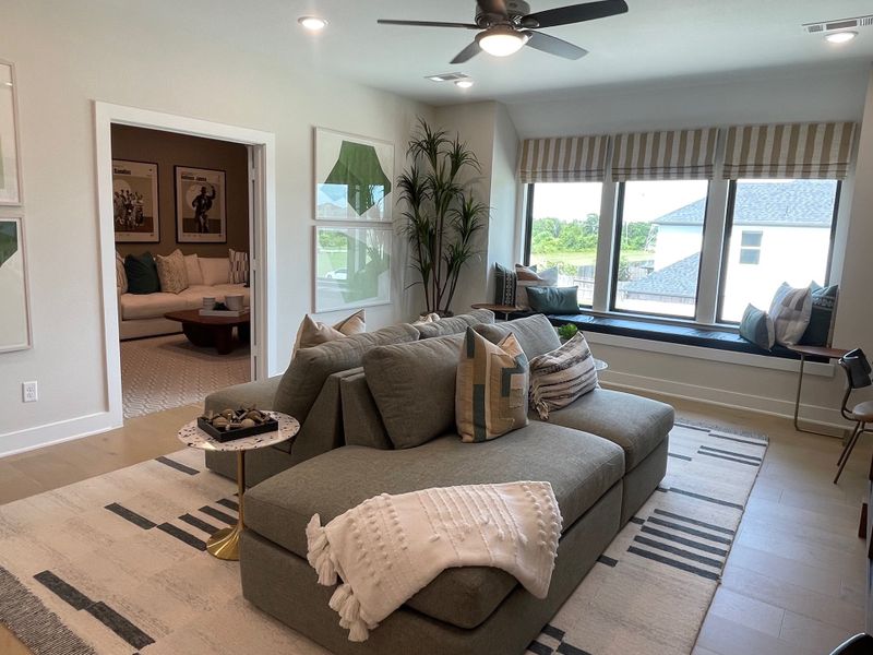 A cozy living room featuring a large gray sofa, stylish decor, and a window seat with natural light streaming in. A cozy living room featuring a large gray sofa, stylish decor, and a window seat with natural light streaming in.