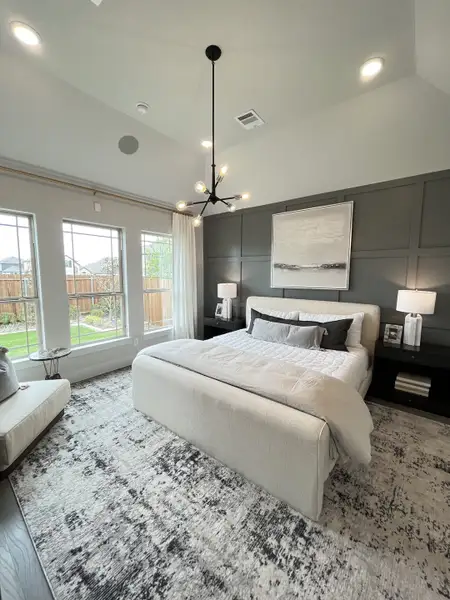 A modern bedroom featuring a cozy bed, elegant chandelier, and large windows overlooking a private garden. A modern bedroom featuring a cozy bed, elegant chandelier, and large windows overlooking a private garden.