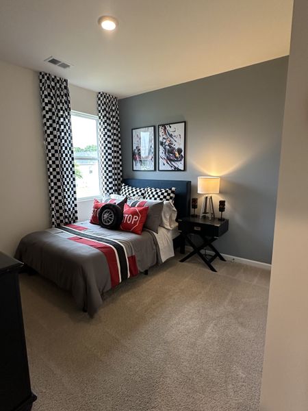A vibrant bedroom featuring racing-themed decor, checkered curtains, and modern art.