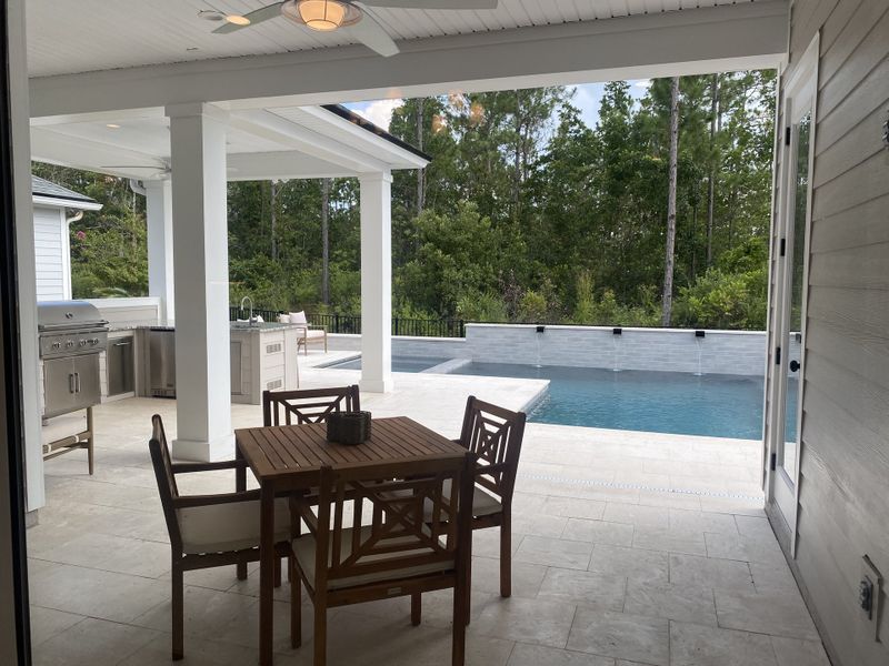 A luxurious outdoor patio with a dining set, built-in grill, and sleek pool, surrounded by lush greenery. A luxurious outdoor patio with a dining set, built-in grill, and sleek pool, surrounded by lush greenery.