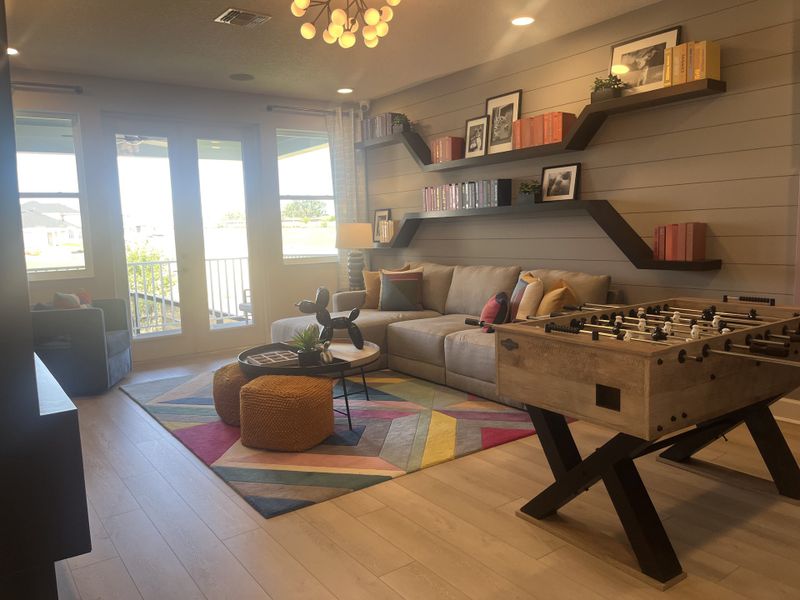 A cozy living area featuring a foosball table, plush sofa, vibrant rug, and stylish shelving with books and decor. A cozy living area featuring a foosball table, plush sofa, vibrant rug, and stylish shelving with books and decor.