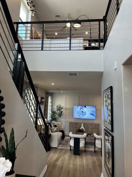 A two-story living room with a sleek metal railing and cozy seating area makes for an airy, open space.