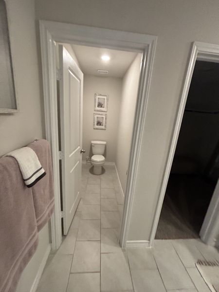 A cozy bathroom with tiled flooring, subtle lighting, and elegant framed artwork for a stylish yet simple design.