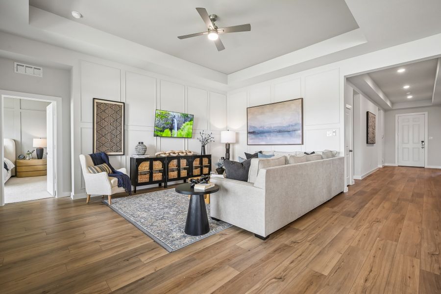 A living room with a large white couch and a wood floor.