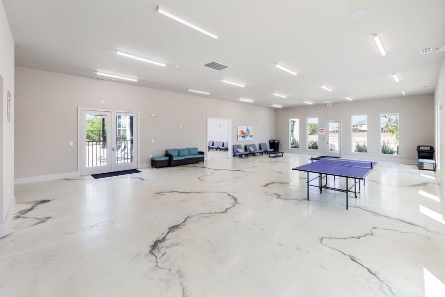Spacious community recreation room with ping pong table, seating area, and polished marble-style floors