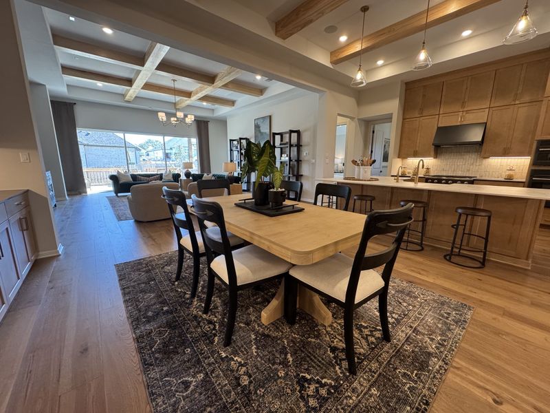A spacious open-concept kitchen and dining area with a wooden table, modern lighting, and cozy living space.