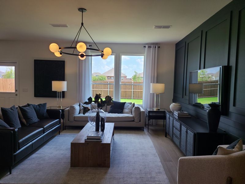 A contemporary living room with elegant seating, a chic chandelier, and a large window overlooking the backyard. A contemporary living room with elegant seating, a chic chandelier, and a large window overlooking the backyard.