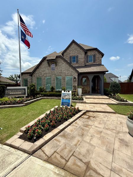 A charming brick home with lush landscaping and a welcoming path in Meridiana: 50ft. lots by Highland Homes (Manvel, TX).