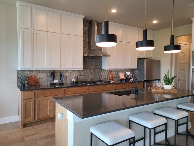 A modern kitchen featuring sleek black countertops, white and wood cabinetry, and stylish pendant lighting. A modern kitchen featuring sleek black countertops, white and wood cabinetry, and stylish pendant lighting.