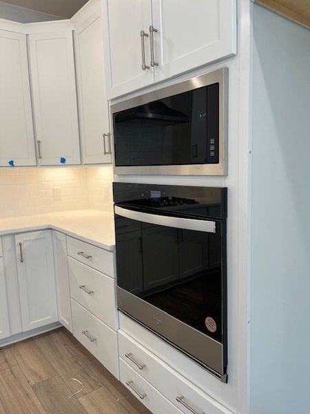 A sleek kitchen with stainless steel appliances, white cabinets, and modern finishes.