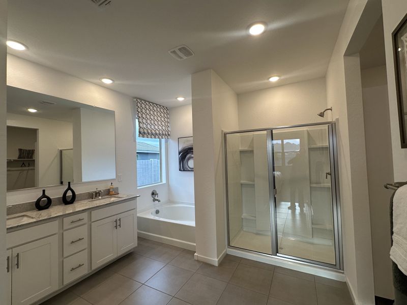 A luxurious primary bathroom with a soaking tub, dual vanity, and a glass-enclosed shower for a spa-like experience.