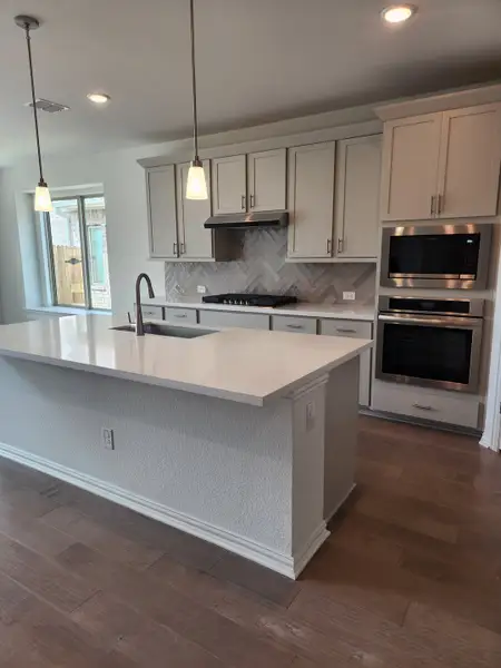 A modern kitchen featuring a large island, herringbone backsplash, sleek cabinetry, and stainless steel appliances. A modern kitchen featuring a large island, herringbone backsplash, sleek cabinetry, and stainless steel appliances.