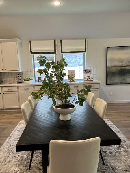 A modern dining area featuring a dark wood table, cream chairs, and large windows with elegant Roman blinds. A modern dining area featuring a dark wood table, cream chairs, and large windows with elegant Roman blinds.