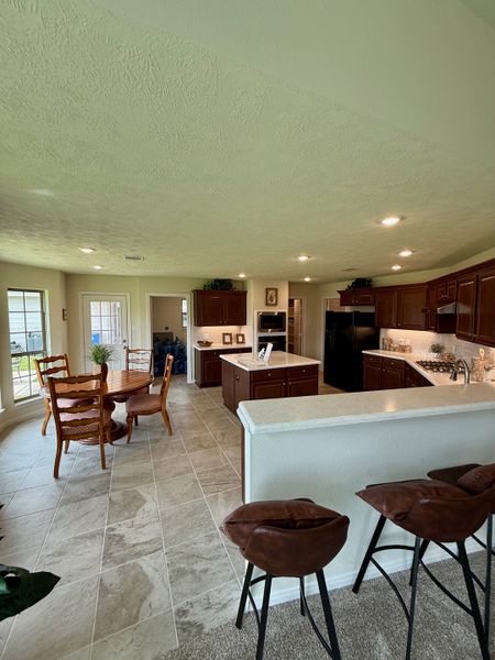 An open-concept kitchen with rich wooden cabinets, a cozy dining area, and modern bar stools.