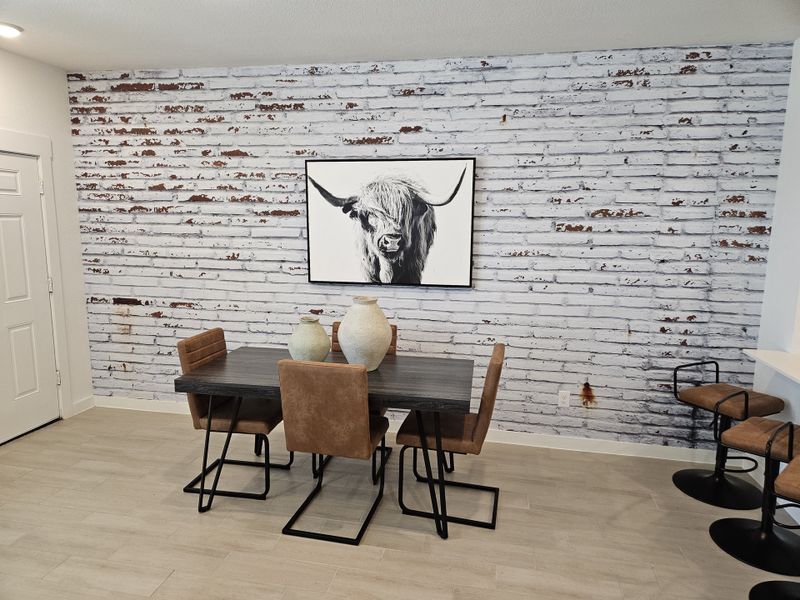 A chic dining area featuring a rustic brick accent wall, modern table, leather chairs, and elegant decor. A chic dining area featuring a rustic brick accent wall, modern table, leather chairs, and elegant decor.