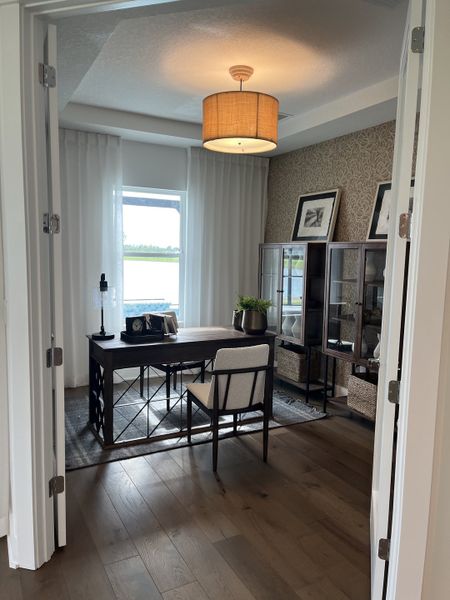 A chic home office with a wooden desk, stylish lighting, and elegant shelving, overlooking a scenic outdoor view.