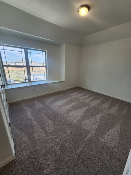 A cozy room with plush carpeting, large window for natural light, and a simple ceiling light fixture. A cozy room with plush carpeting, large window for natural light, and a simple ceiling light fixture.