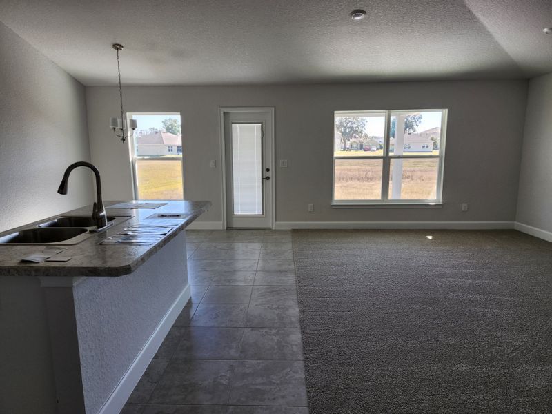 An open layout with a granite kitchen island, tile flooring, and large windows providing natural light.