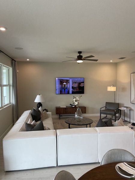 A modern living room featuring a sleek white sectional sofa, contemporary decor, and a wall-mounted TV. A modern living room featuring a sleek white sectional sofa, contemporary decor, and a wall-mounted TV.