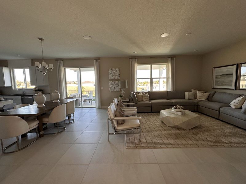 A bright living room with neutral décor, a sectional sofa, and contemporary accents in Landings at Lake Mabel Loop by KB Home (Dundee, FL).