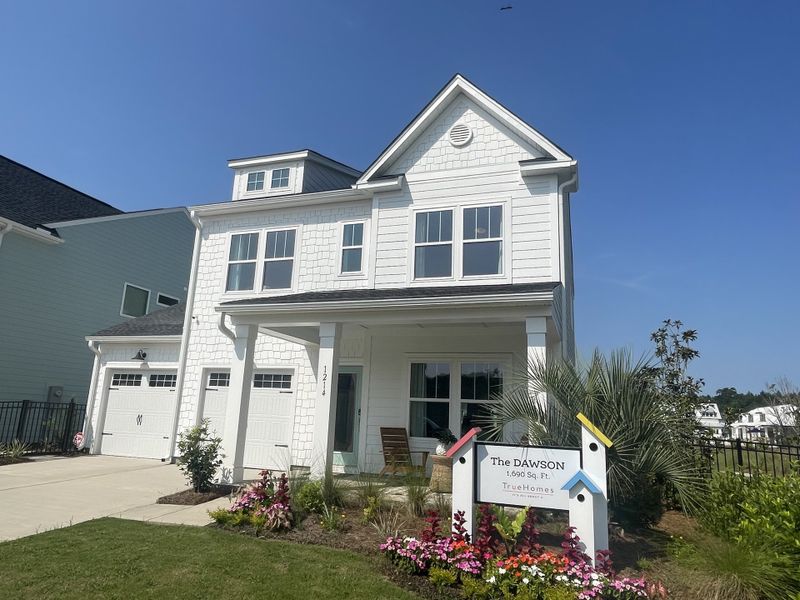 Elegant two-story white home with charming windows and landscaped yard in Homecoming by True Homes (Ravenel, SC).