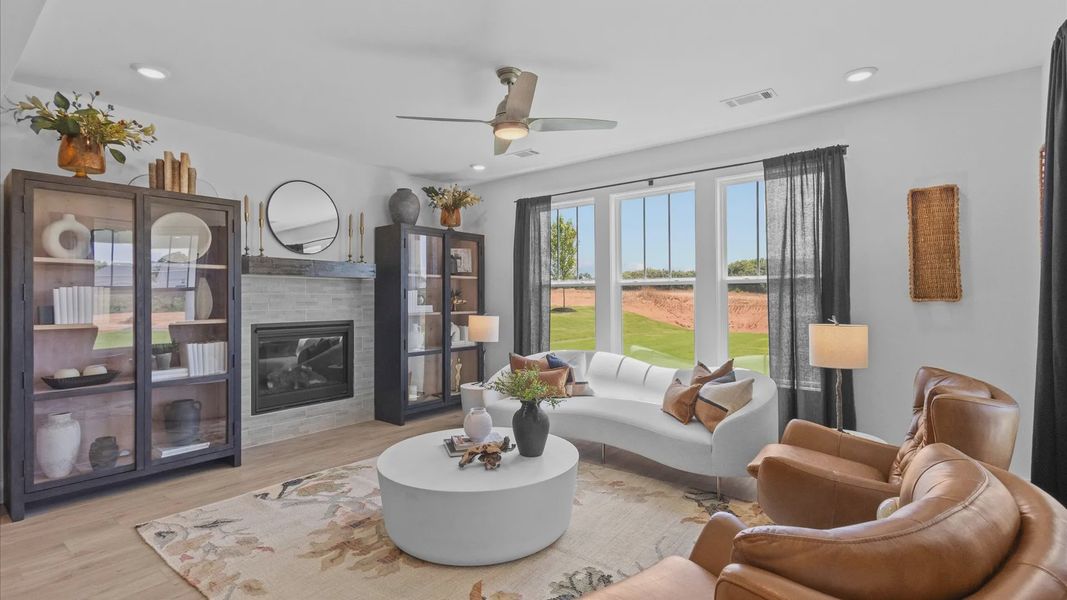 Cozy family room with elegant stone fireplace, ceiling fan, and large bay window with hardwood flooring in Anderson, SC