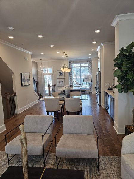 A modern open living space with plush seating, hardwood floors, and elegant lighting leading to a dining area.