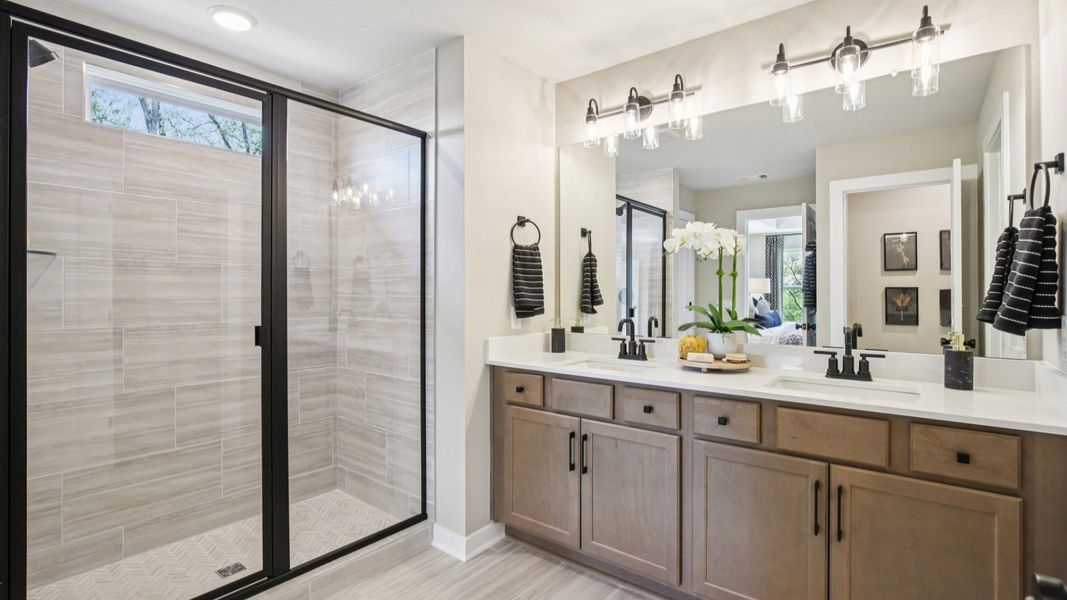 Large bathroom with tiled shower in glass enclosure, and dual vanity