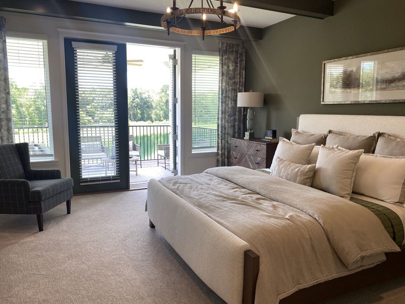 A serene bedroom with a plush bed, elegant lighting, and large windows opening to a lush balcony view.