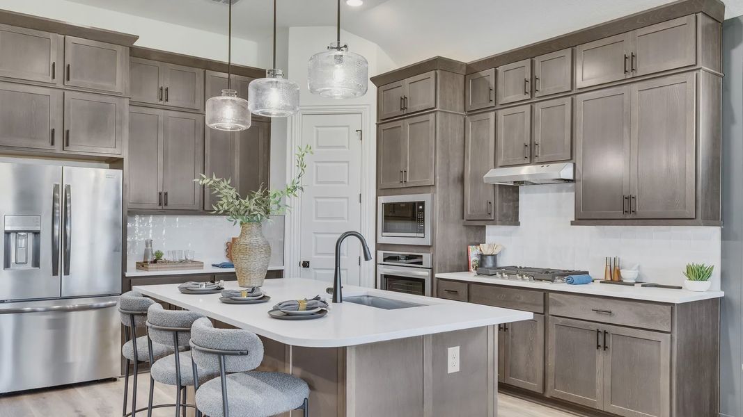 Elegant gray cabinetry, pendant lighting, and a quartz island elevate this Briarwood kitchen.