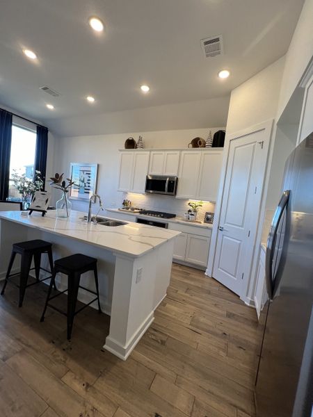 A bright, modern kitchen featuring white shaker cabinets, quartz countertops, and a spacious island.