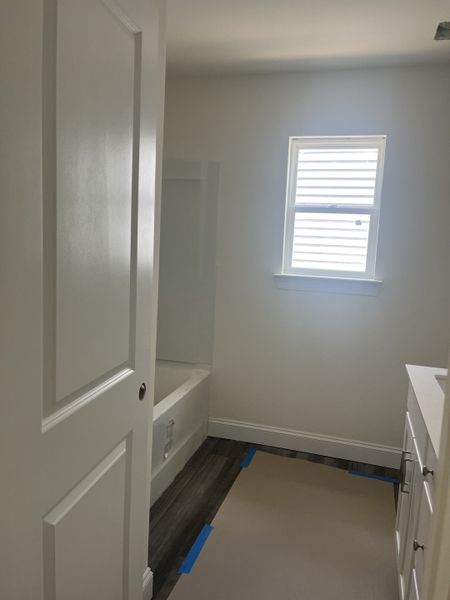 A bright bathroom with a white tub, a window for natural light, and sleek flooring, perfect for a minimalist look. A bright bathroom with a white tub, a window for natural light, and sleek flooring, perfect for a minimalist look.