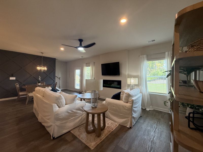 A cozy living area with white armchairs, dark accent wall, modern fireplace, and a stylish chandelier. A cozy living area with white armchairs, dark accent wall, modern fireplace, and a stylish chandelier.