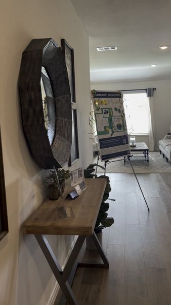 A modern entryway with a sleek console table, decorative mirror, and a cozy living room in the background.