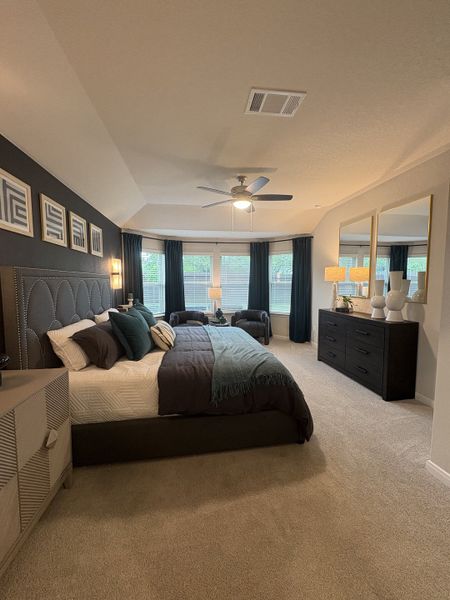 A spacious bedroom with elegant dark accents, plush carpeting, and large windows for natural light. A spacious bedroom with elegant dark accents, plush carpeting, and large windows for natural light.