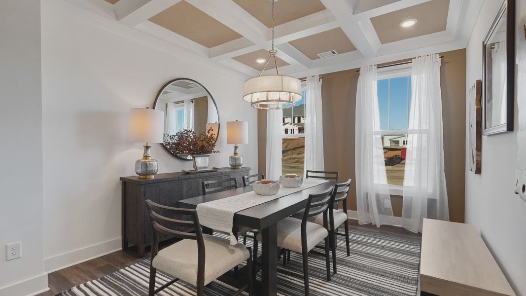 Stunning coffered ceiling dining room with chandelier, large windows, and hardwood flooring at Walnut Ridge by DRB Homes