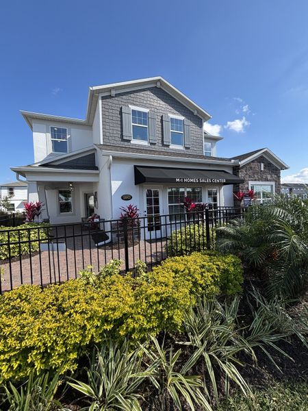 A beautiful sales center with a charming exterior and lush greenery in Eden at Crossprairie by M/I Homes (St. Cloud, FL).